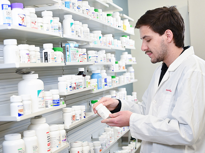 A pharmacy student stands in a pharmaceutical studies simulation space.