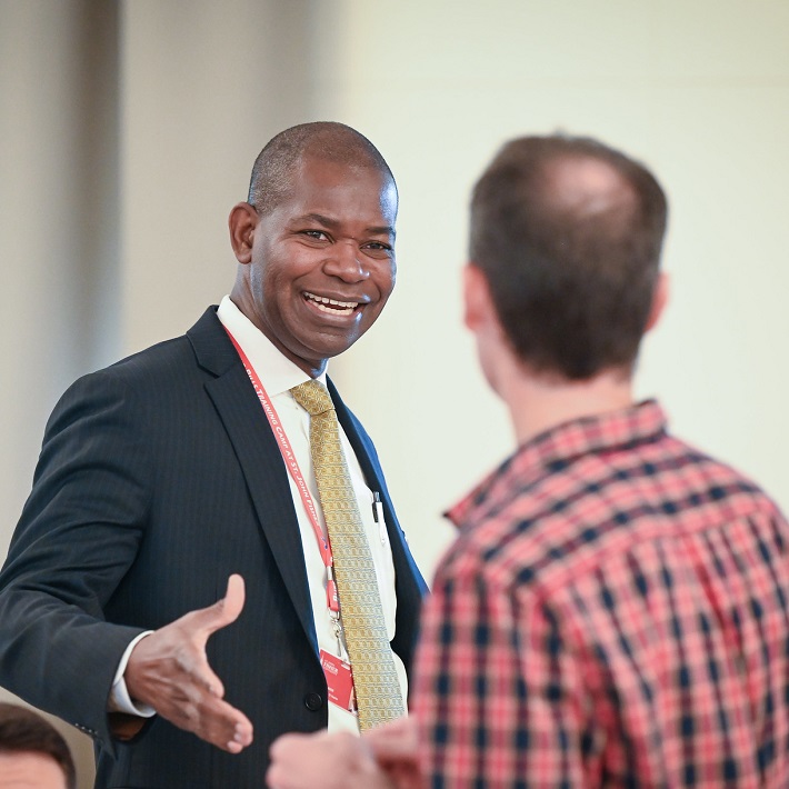 Mark is smiling and extending his arm for a handshake at Service Recognition Luncheon