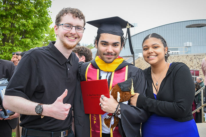 Students stand together in commencement regalia.