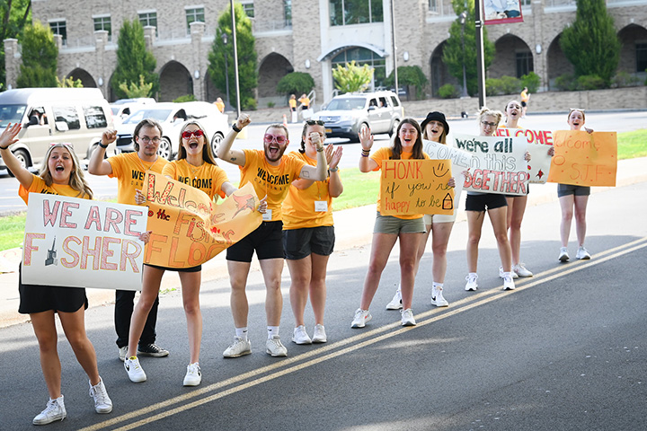 Students welcomes new students to campus with Welcome Home signs.
