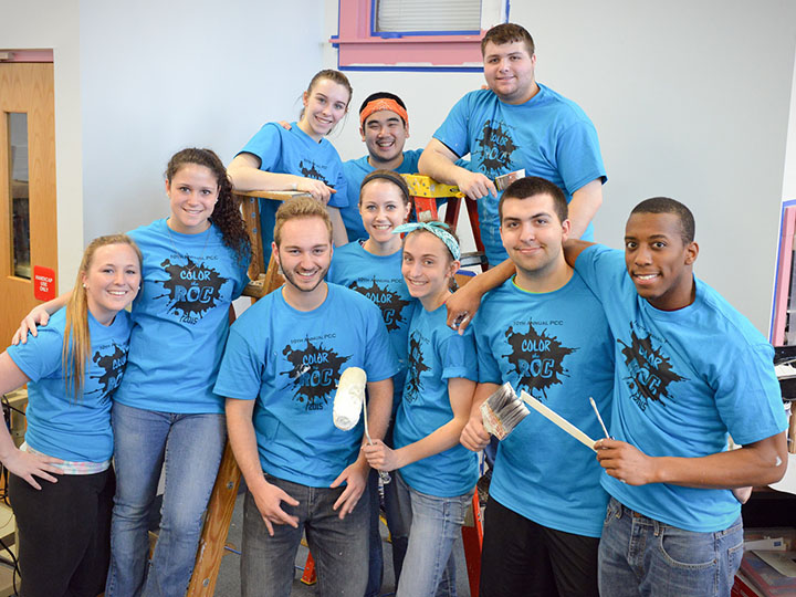 Students help paint an area school during the annual Project Community Convergence event.