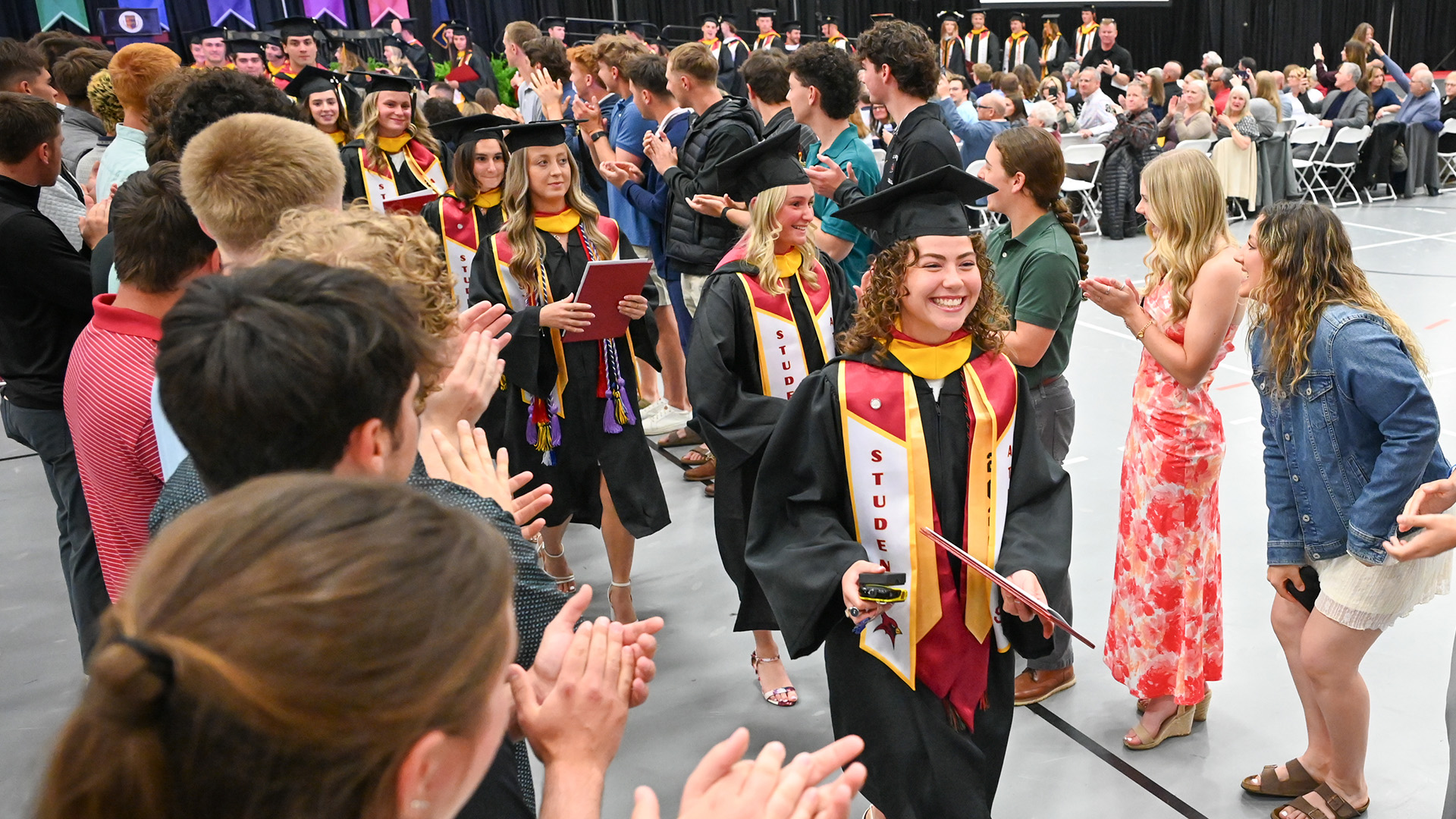 Students in commencement regalia process during the athletics ceremony.