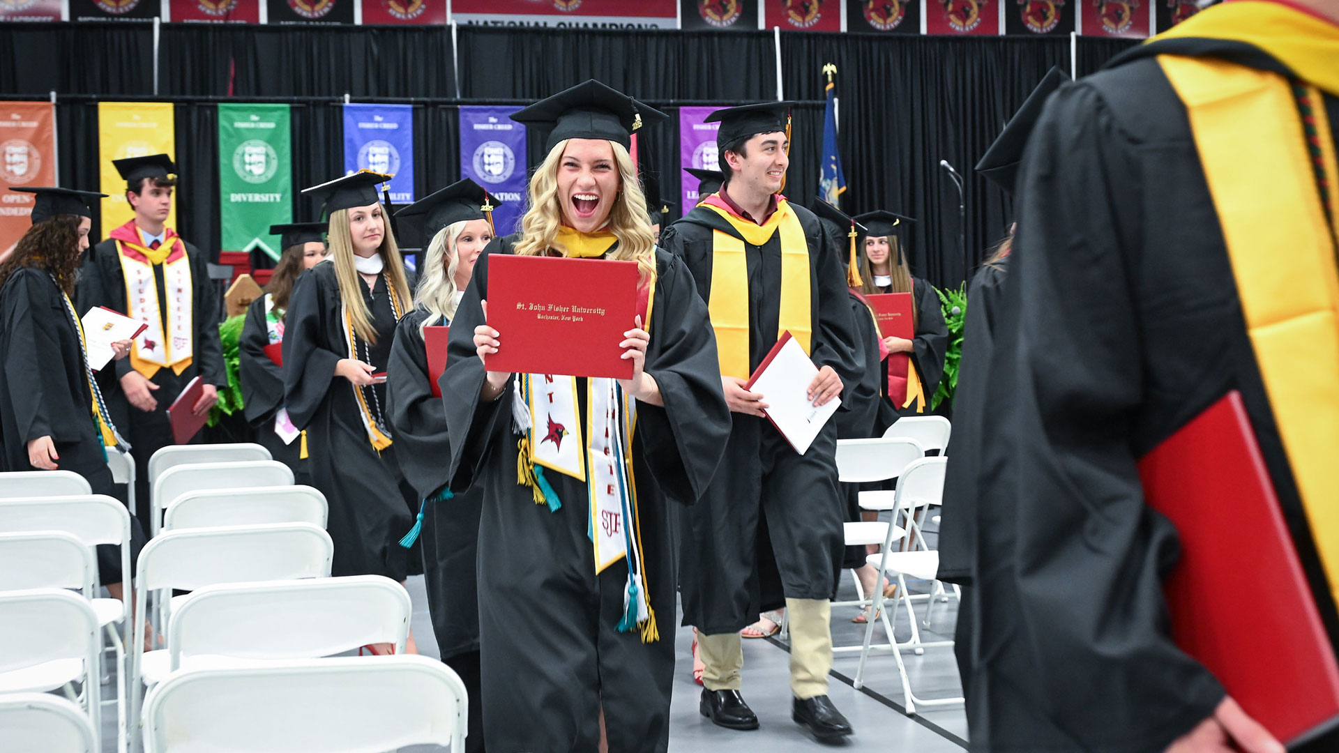 A smiling graduate in commencement regalia.