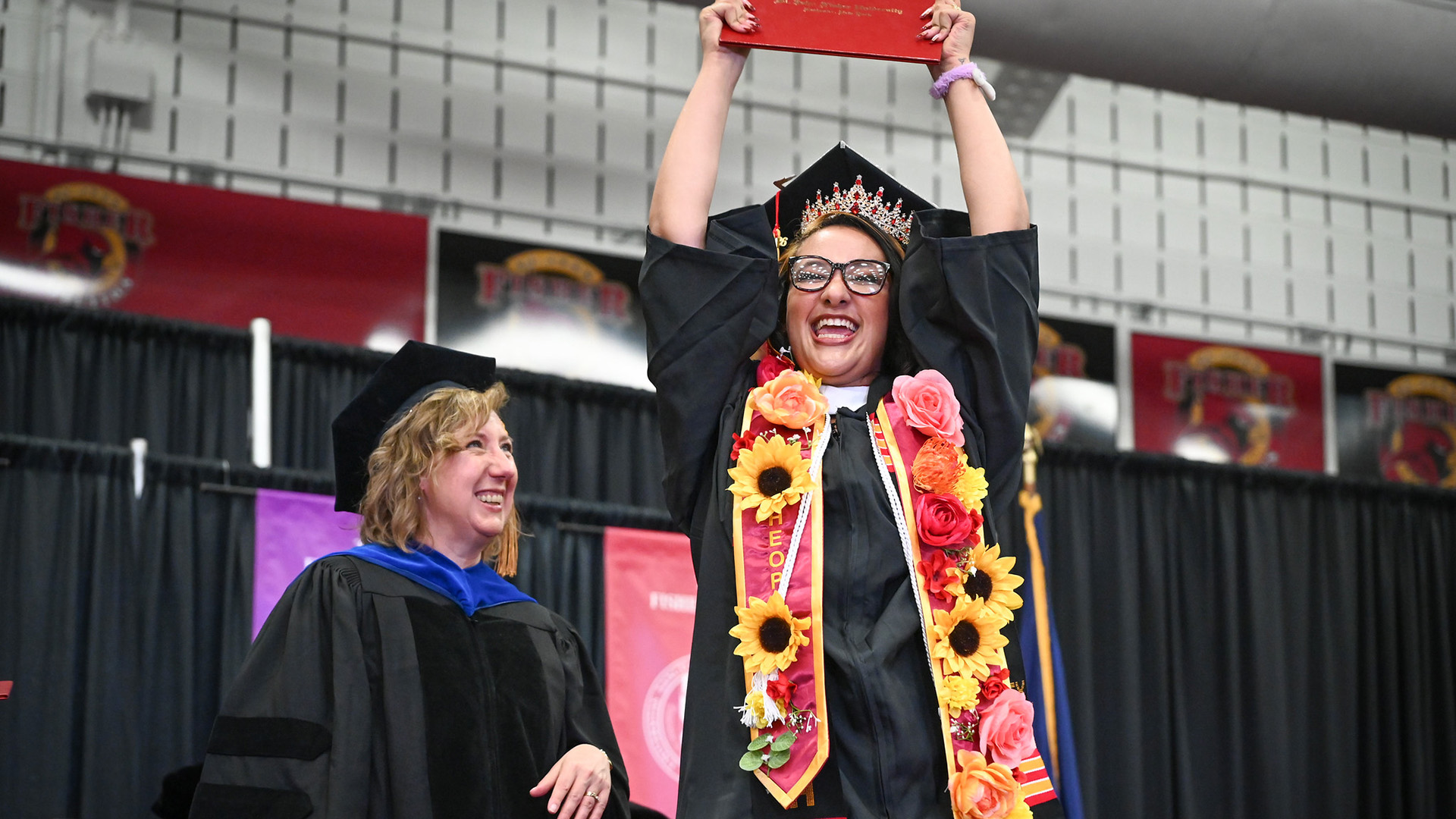 A graduating student holds he diploma high in celebration during commencement ceremonies.