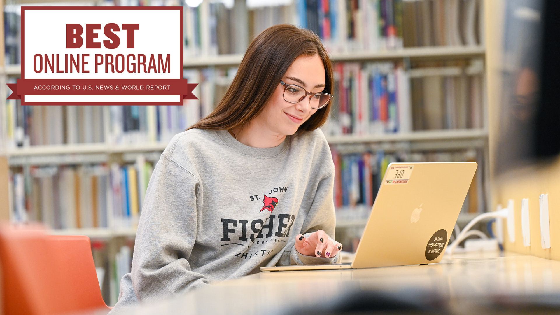 A student works on a laptop in a library near icon for Best Online Program according to US News & World Report.