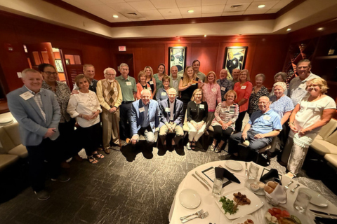 Alumni gathering for a group photo at a restaurant in Sarasota