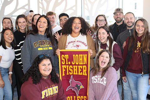 Alumni stand together before a wedding holding a St. John Fisher banner.