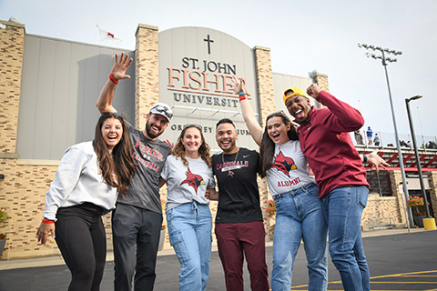 Alumni of St. John Fisher University stand together outside of the stadium on campus.