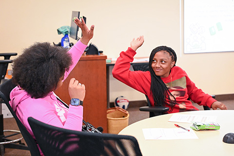 Students high five during business camp.