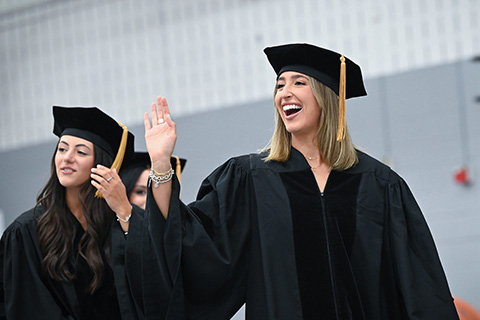 A student waves in the crowd during Commencement