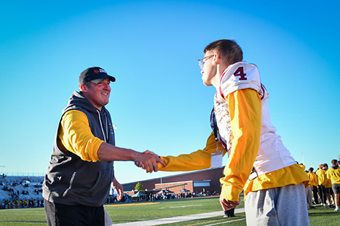 Coach shakes honorary coach's hand.
