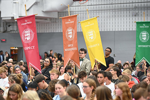 Students carry banners for the Fisher Creed to represent values of respect, open-mindedness, integrity, diversity, and responsibility.