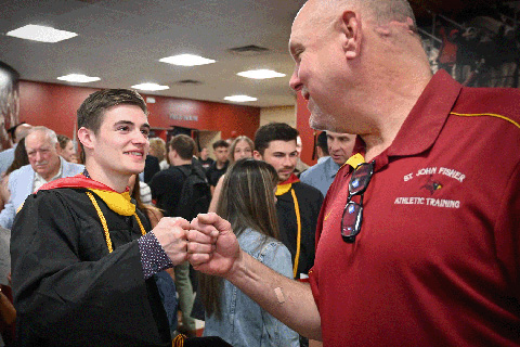 A student fist bumps an athletic coach.