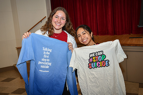 Students hold t-shirts at the Out of the Darkness Walk to promote mental health awareness to prevent suicide.
