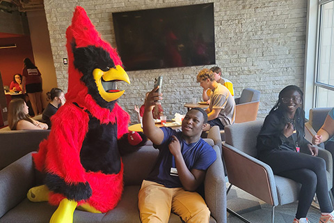 Cardinal sits with students on break during Cardinal Nurse Camp