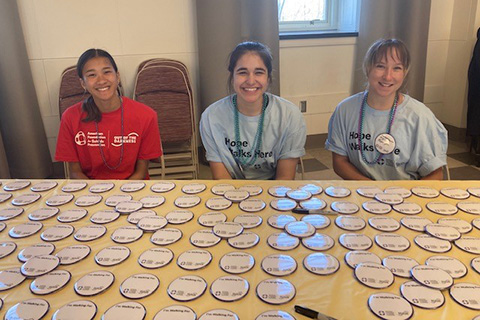 Student volunteers offer participants Out of the Darkness Walk pins.