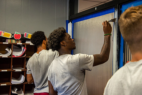 Members of the Fisher football team paint a classroom in the community.