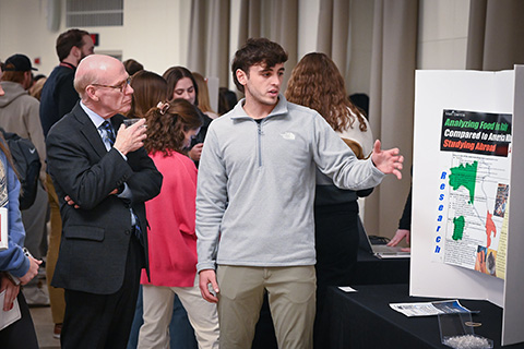 President Rooney listens to a student explain his research.