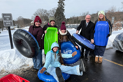 Dr. Rooney stands with students tubing on the hill near Kearney.