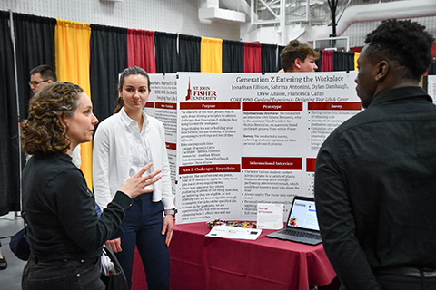 A student shares research on a poster at the Fisher Showcase.