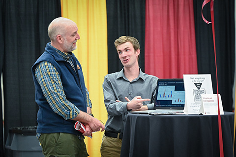 Students and professors discuss student research on display at the Fisher Showcase.