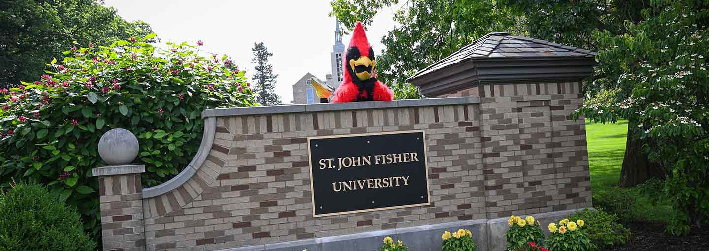 Cardinal mascot on brick sign of St. John Fisher University.