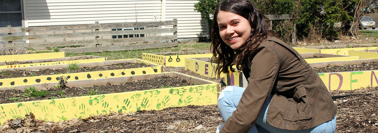 A student works in a community garden as part of a community-engaged learning course.