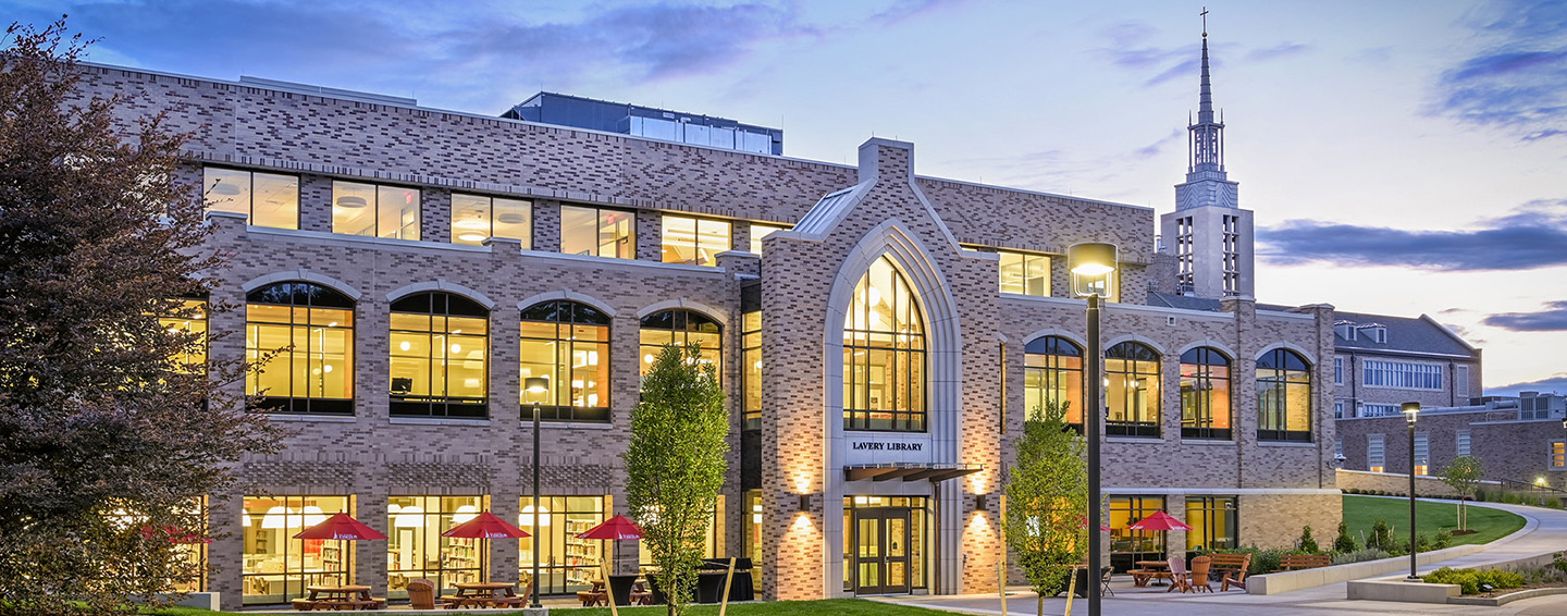 Lavery Library brightly lit in the evening with iconic Kearney Hall as a backdrop.