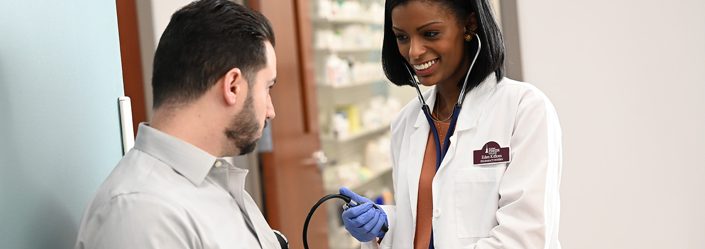 A pharmacy student practices taking a blood pressure reading.