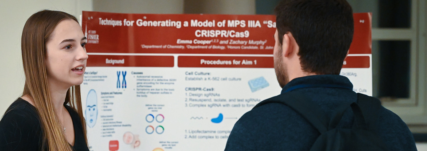 A student shares information about research near a printed poster.