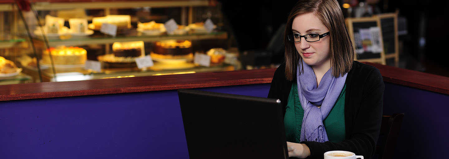 Student with laptop in cafe.