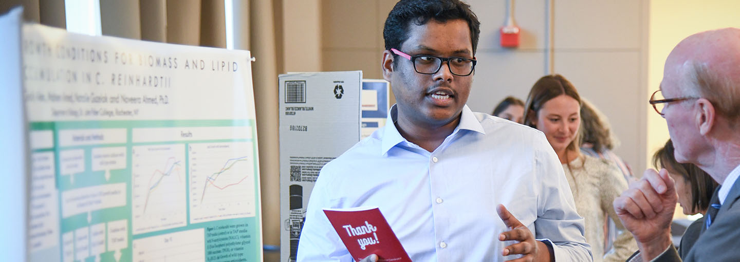 A student explains poster research presentation to St. John Fisher University President Rooney.