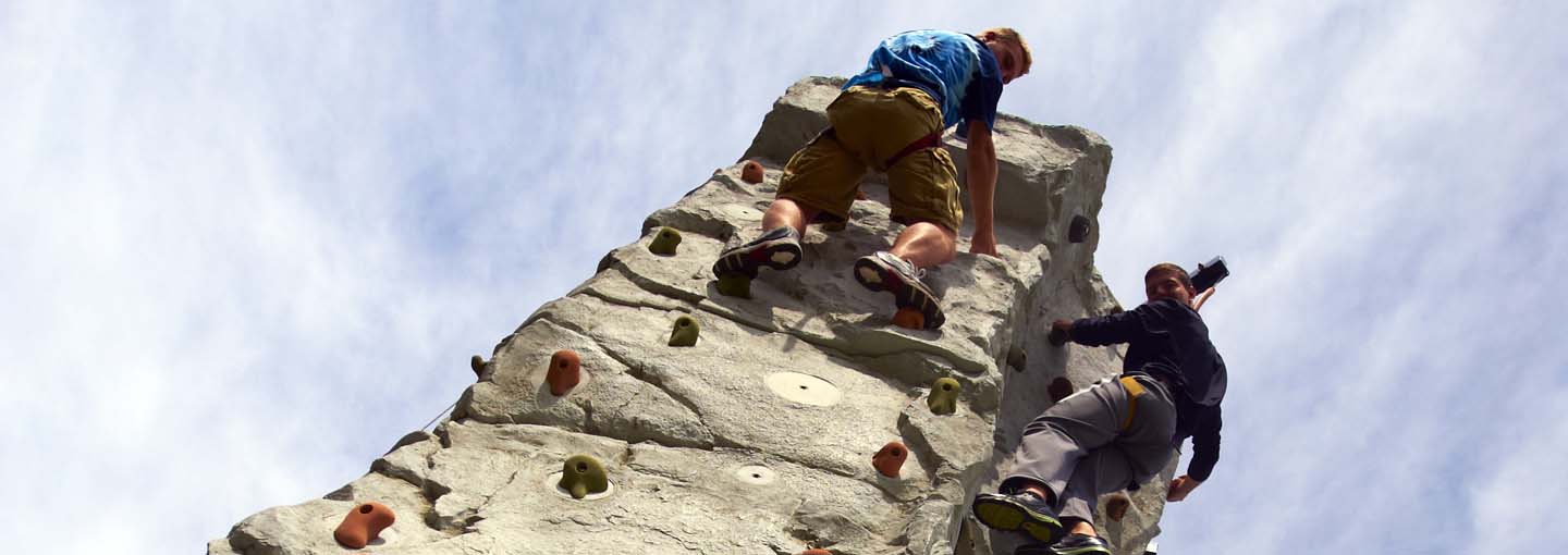 Two students on rock wall.