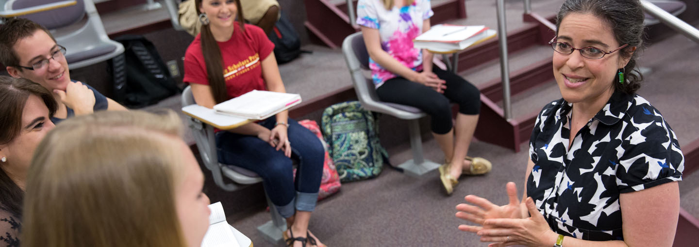 Professor Deb Uman in front of classroom.