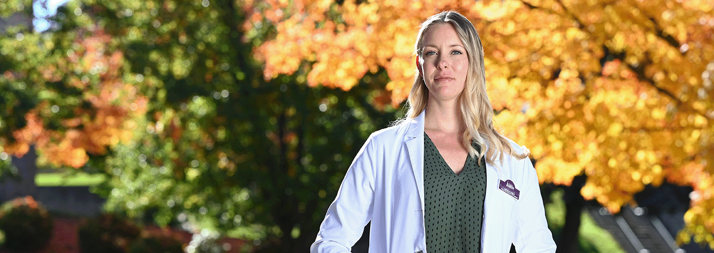 A CRNA student stands confidently outside of the Wegmans School of Nursing.