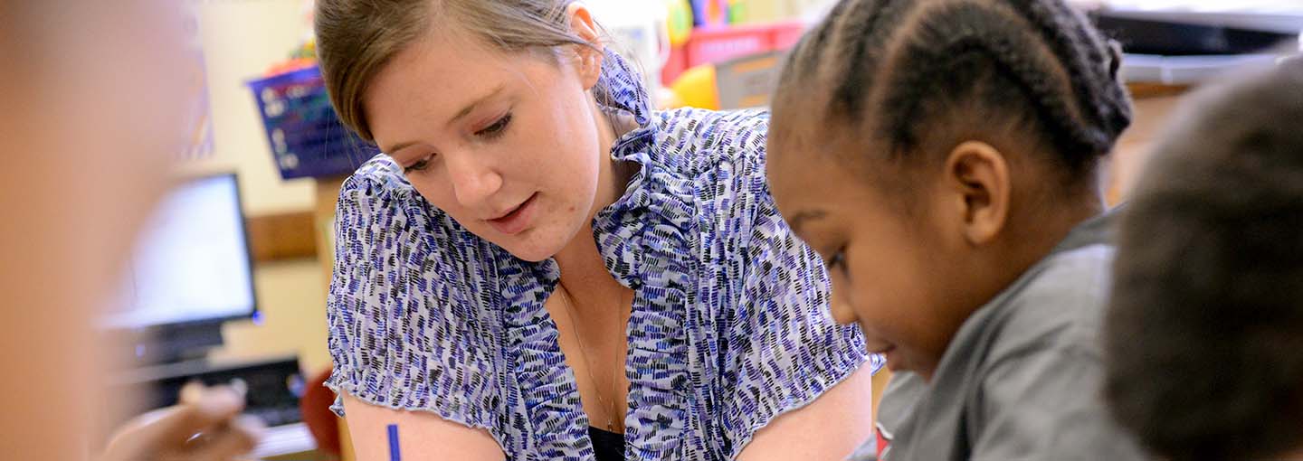 Student teacher with young student writing