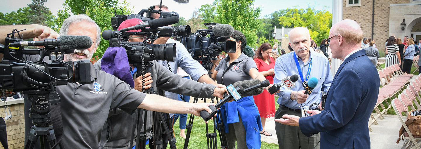 Members of the press interview Dr. Rooney at a press conference at St. John Fisher University.