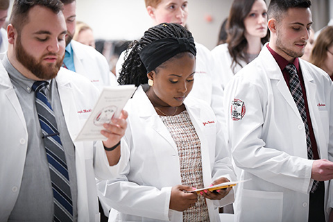 Students in white coats at the annual Wegmans School of Pharmacy White Coat Ceremony.