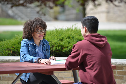 Students talking outdoors at St. John Fisher University campus.