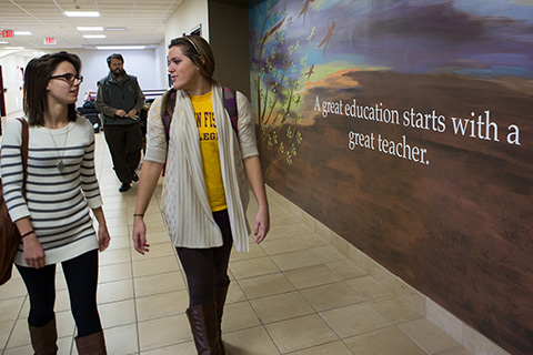 Students walking next to a mural with text 