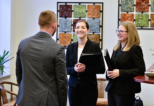 Three students in business attire speak in the Career Center