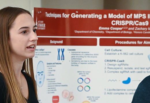 A student shares research on a poster at the Fisher Showcase.