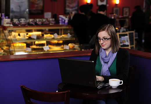 Student with laptop in cafe.