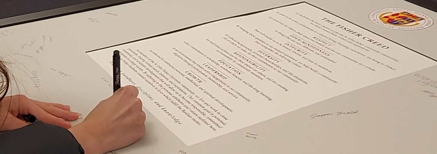 A student signing the Fisher Creed.