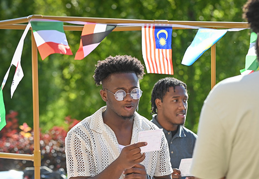 A student visits a booth with flags representing multiple countries at the Inclusion Dinner event at Fisher.