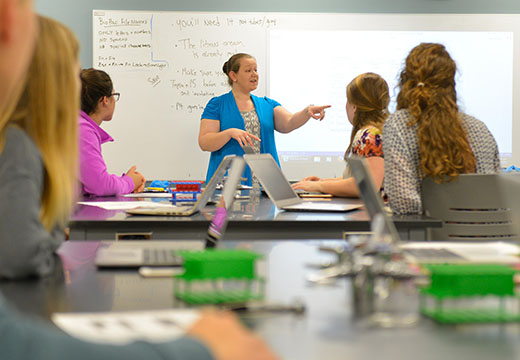 Faculty member pointing at front of science classroom.