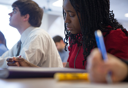 Student writing in a classroom.