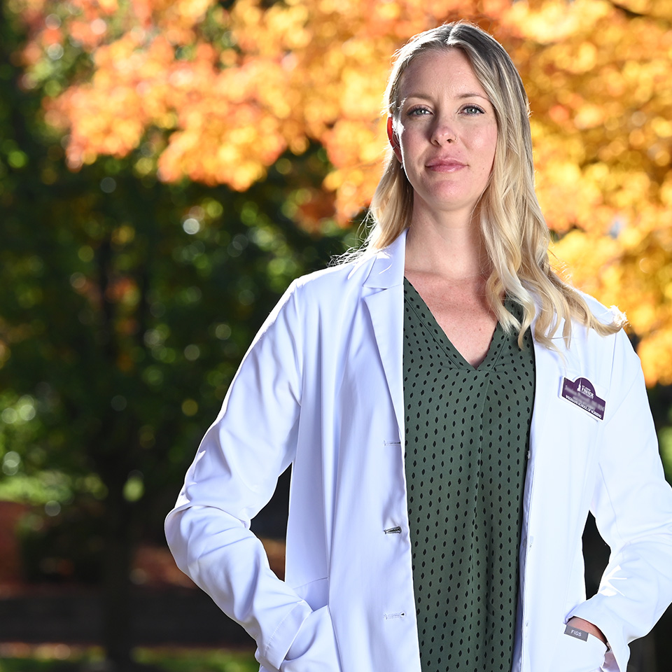 A nursing student stands confidently outside of the Wegmans School of Nursing.