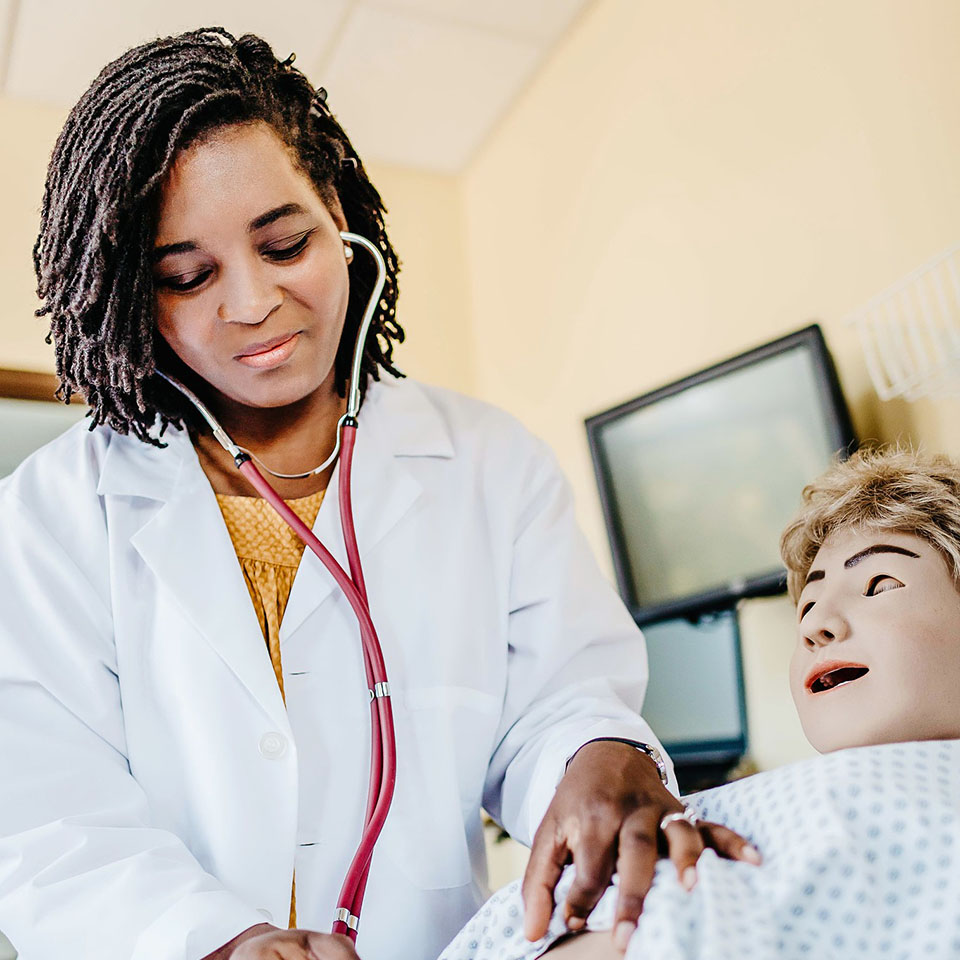 A nursing student uses a stethoscope during simulation.